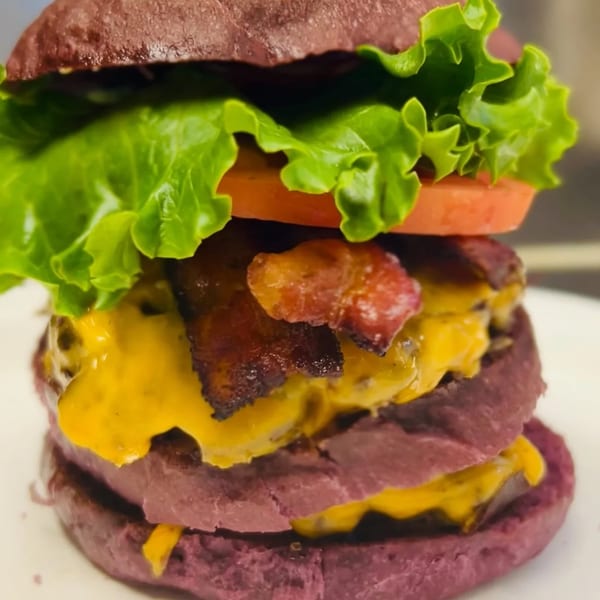 Taro Hut's double cheeseburger with bacon, lettuce, and tomato on a purple taro bun.