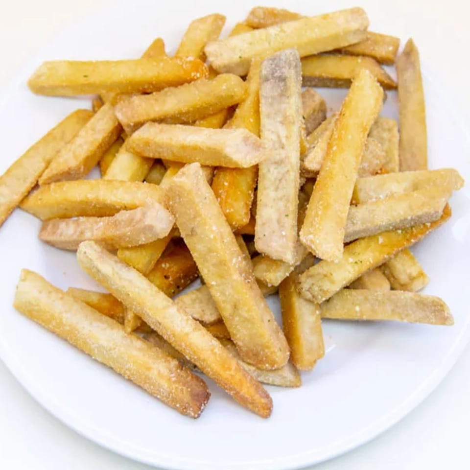 A white plate piled high with golden-brown, crispy taro fries, lightly seasoned.